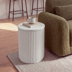 Ayla Fluted 40cm Round Side Table White beside the arm of a sofa on a rug, closer view with a mug on a book