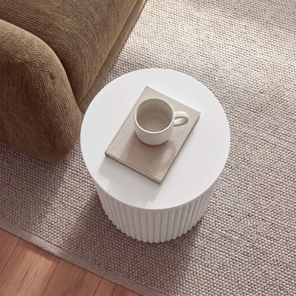 Ayla Fluted 40cm Round Side Table White seen from above beside a sofa, with a mug on a book