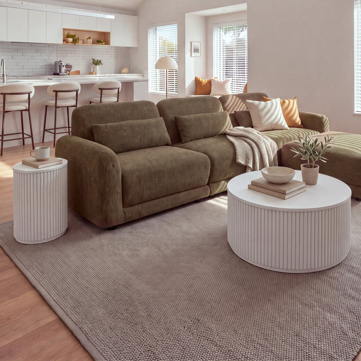 Ayla Fluted 90cm Round Coffee Table White in an open-plan living room with a kitchen behind and a matching fluted side table beside the sofa, wide view