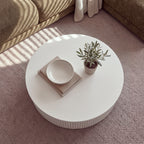 Ayla Fluted 90cm Round Coffee Table White seen from above on a rug, with a bowl on books and a small potted olive tree