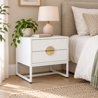 Cortez 2 Drawer Bedside Table White, beside a bed with a table lamp on top