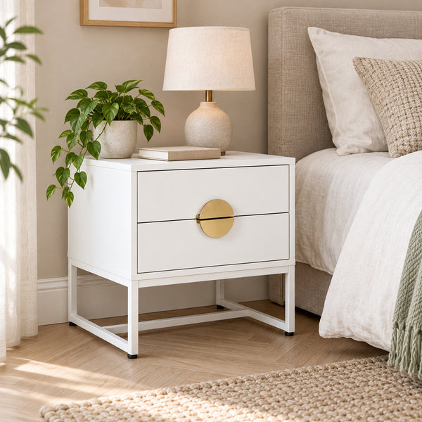 Cortez 2 Drawer Bedside Table White, beside a bed with a table lamp on top