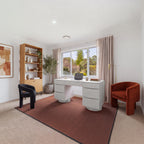 Dorit 172cm 7 Drawer Home Office Desk White in a home office with a dark red rug, a bookshelf and two armchairs, wide view