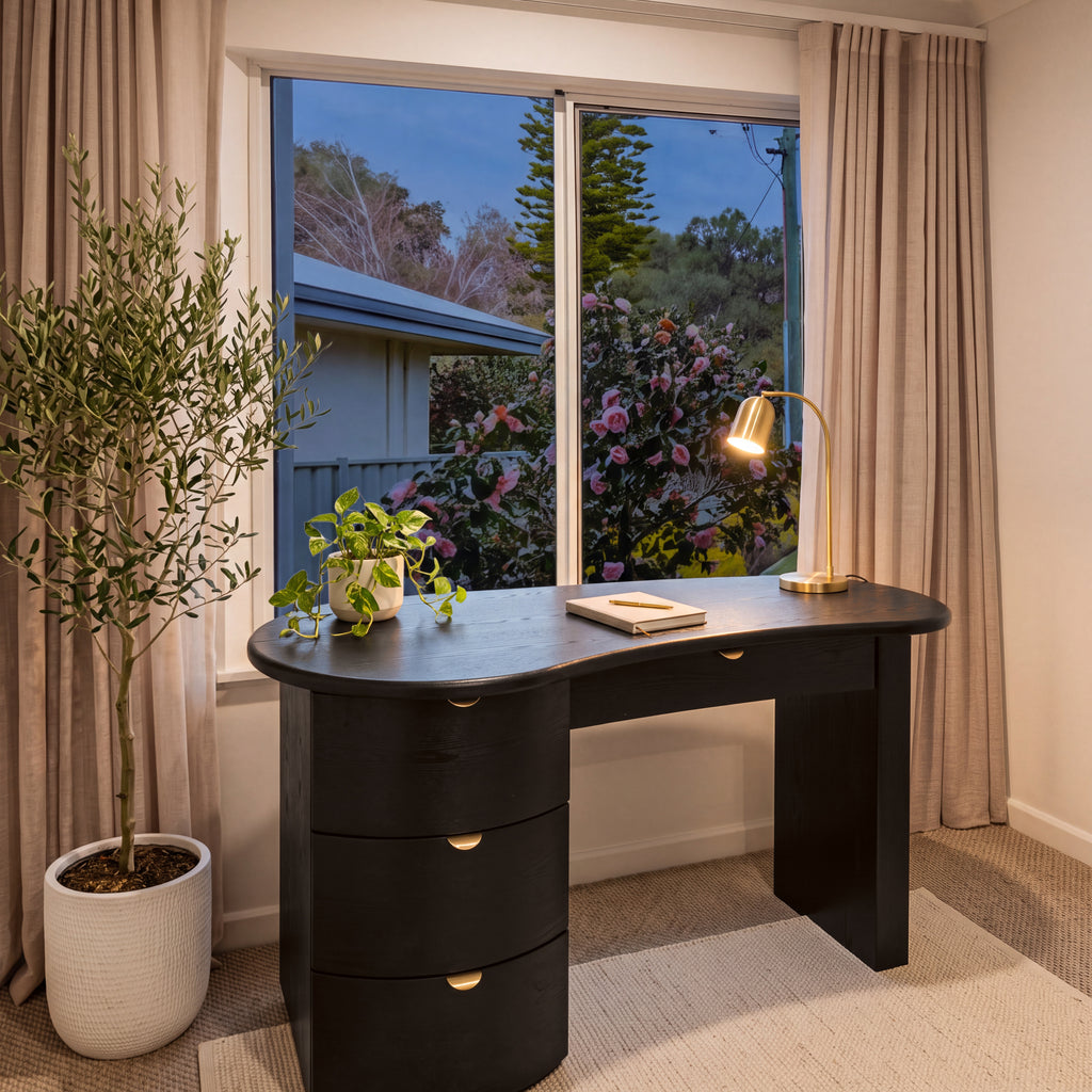 Golborne 150cm Home Office Desk Black in a study by a garden window at dusk, with a brass desk lamp and an olive tree