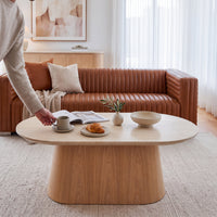 Hera 130cm Coffee Table Natural, in a living room beside a leather sofa