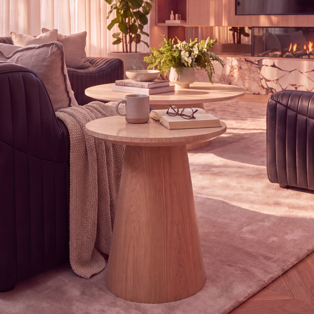 Hera 55cm Round Side Table Natural, styled with a mug and books beside a sofa