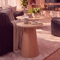 Hera 55cm Round Side Table Natural, styled with a mug and books beside a sofa