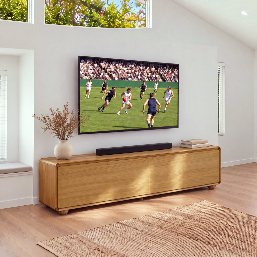 Hudson Jenny 220cm ETU Entertainment TV Unit Natural under a wall-mounted TV with a soundbar, a vase of dried stems and books on top, a jute rug in front