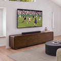 Hudson Jenny 220cm ETU Entertainment TV Unit Walnut under a wall-mounted TV with a soundbar on top, a fluted round coffee table and rug in front