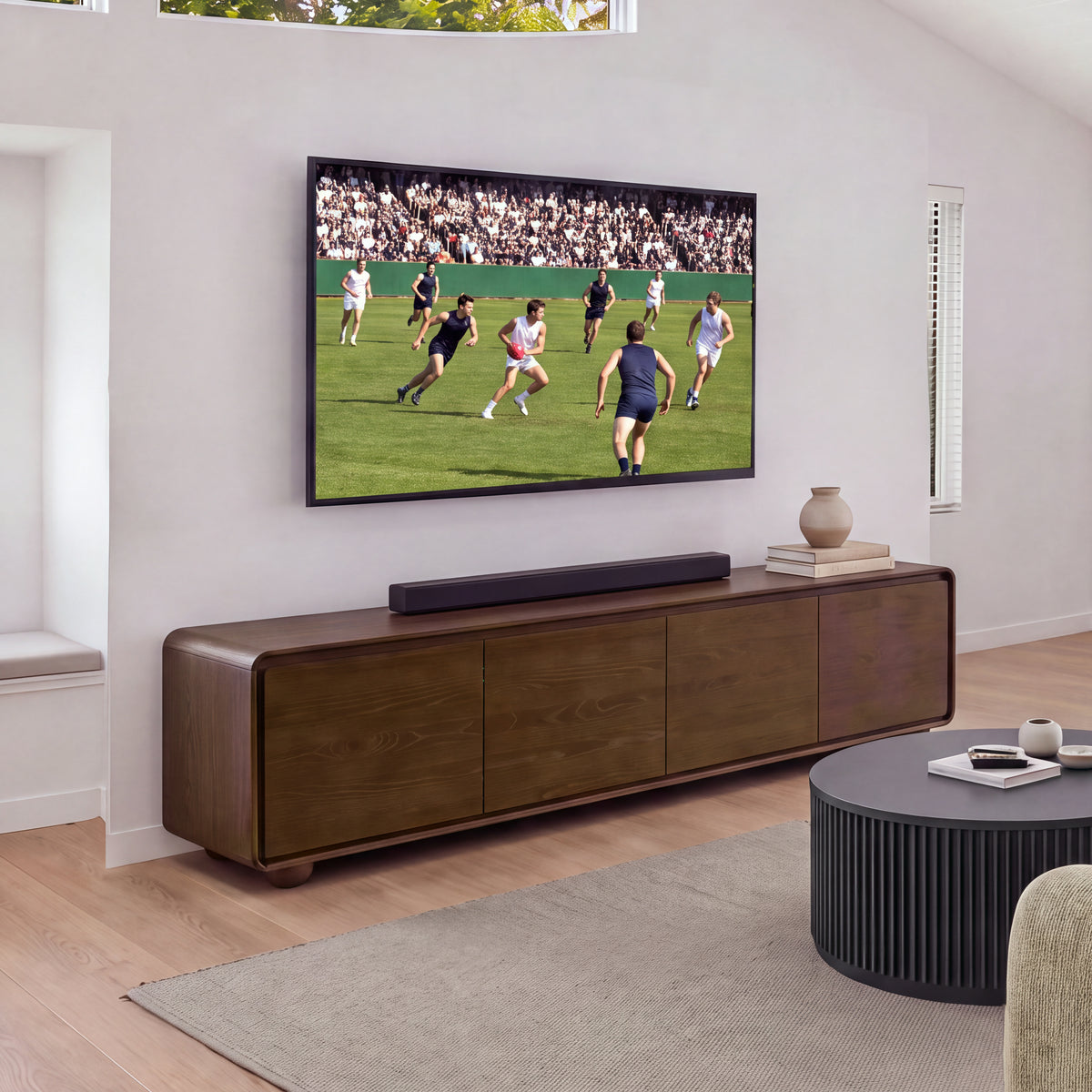 Hudson Jenny 220cm ETU Entertainment TV Unit Walnut under a wall-mounted TV with a soundbar on top, a fluted round coffee table and rug in front