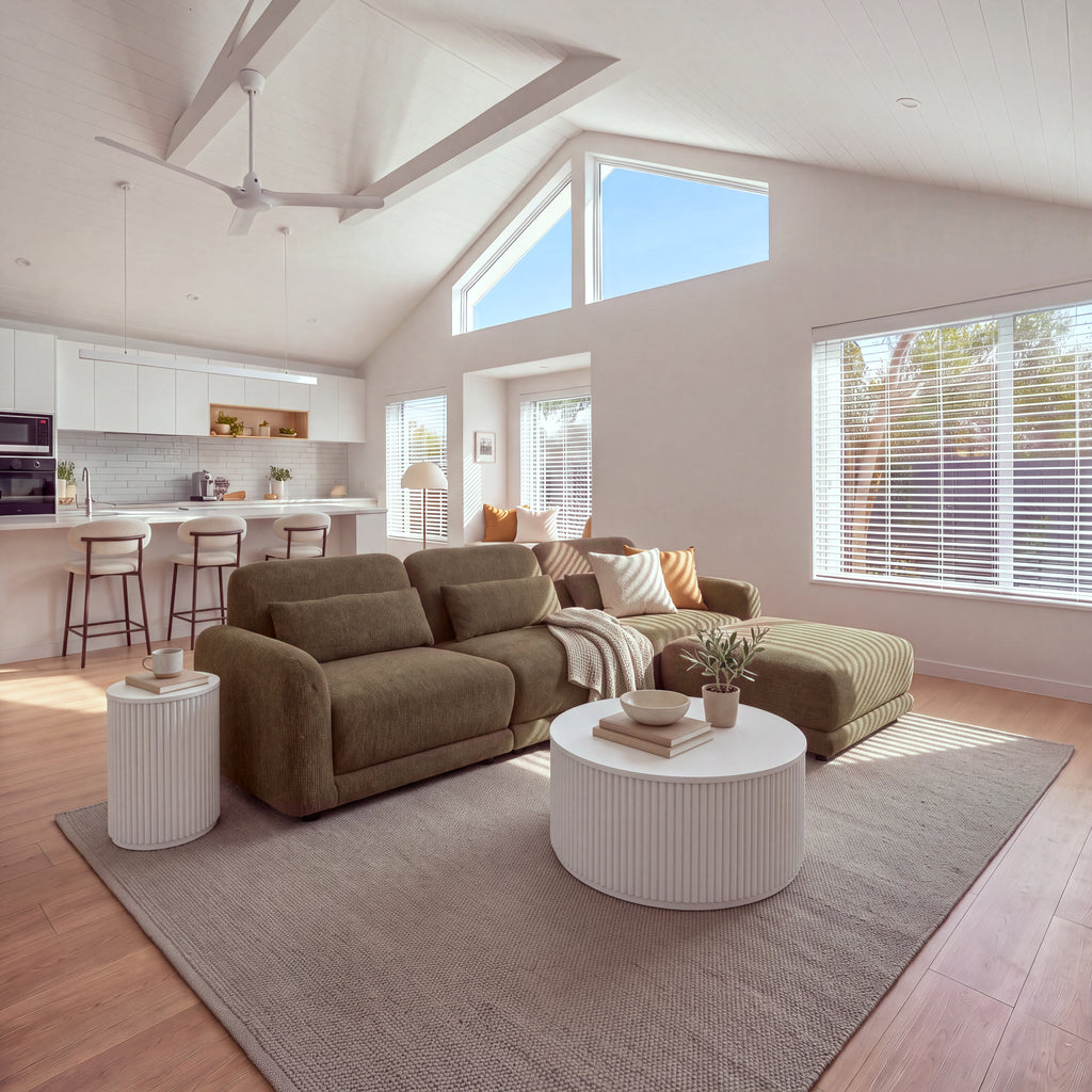 Paulie 270cm 3 Seater Modular Sofa with Ottoman Chocolate in an open-plan living room with a raked ceiling, a kitchen island and round white fluted tables, wide view