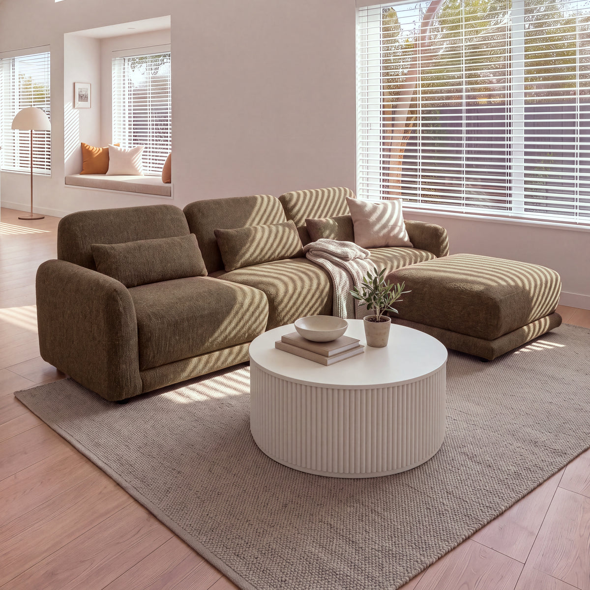 Paulie 270cm 3 Seater Modular Sofa with Ottoman Chocolate with the ottoman as a chaise on the right, by a window with blinds