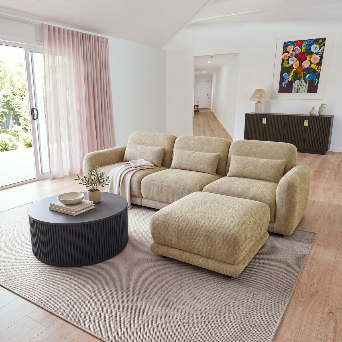 Paulie 270cm 3 Seater Modular Sofa with Ottoman Latte with the ottoman pushed against the right seat as a chaise, by sheer curtains