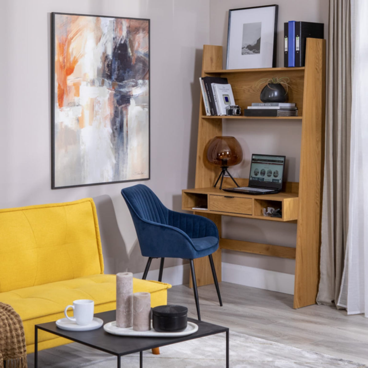Scala 100cm Study Desk with Shelves Oak, in a living room beside a blue armchair