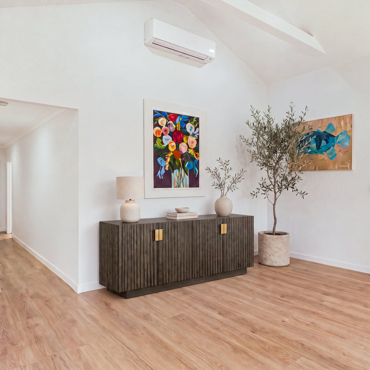 Sloane 180cm Buffet Table Storage Cabinet Grey Oak in a bright room beside a hallway, with a floral painting above and an olive tree in the corner, wide view