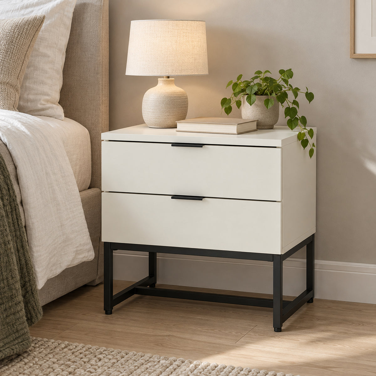 Svana 2 Drawer Bedside Table White, beside a bed with a table lamp on top
