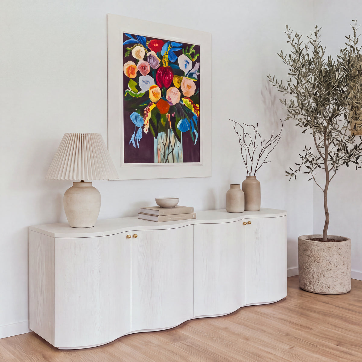 Wave white buffet under a floral painting in a bright dining room, front three-quarter view