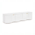 Wave 215cm white four-door entertainment unit with a curved wave front and brass knobs, angled view on a white background
