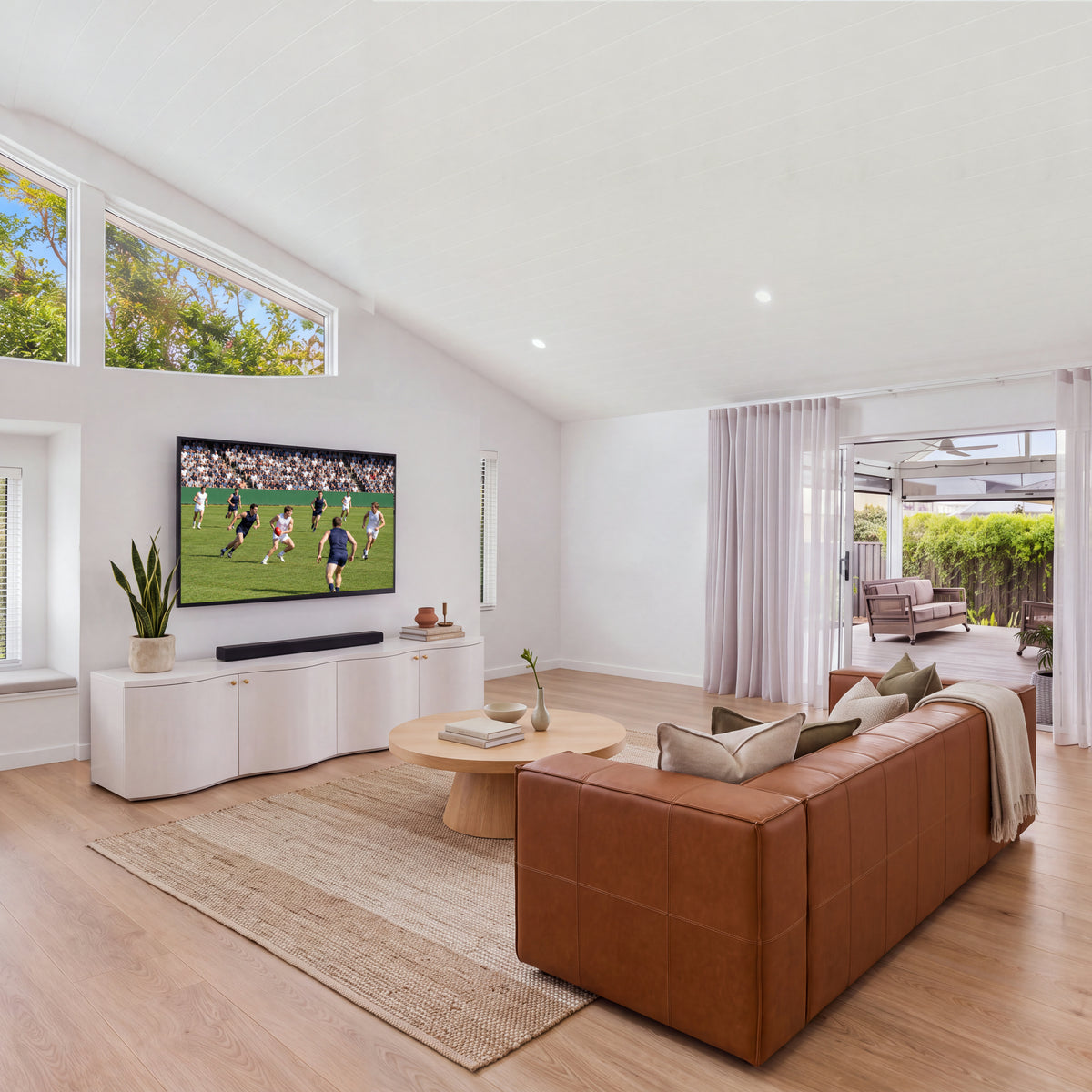 Wave white entertainment unit in a sunlit living room with a sofa and round coffee table, wide view